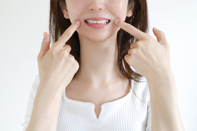 イーッと開けた口元を指さしている女性